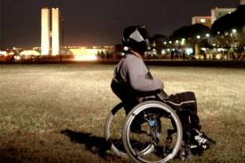 film still from White Out, Black In. Man in wheelchair wearing futuristic helmet.